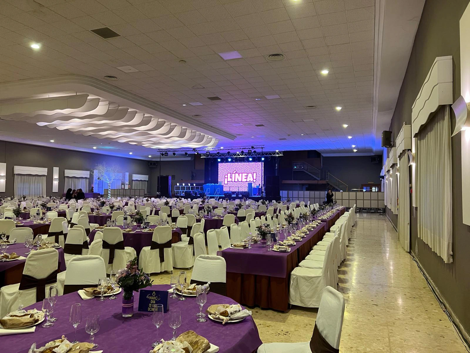 Gran salón con mobiliario de mesas y sillas dispuestos para evento