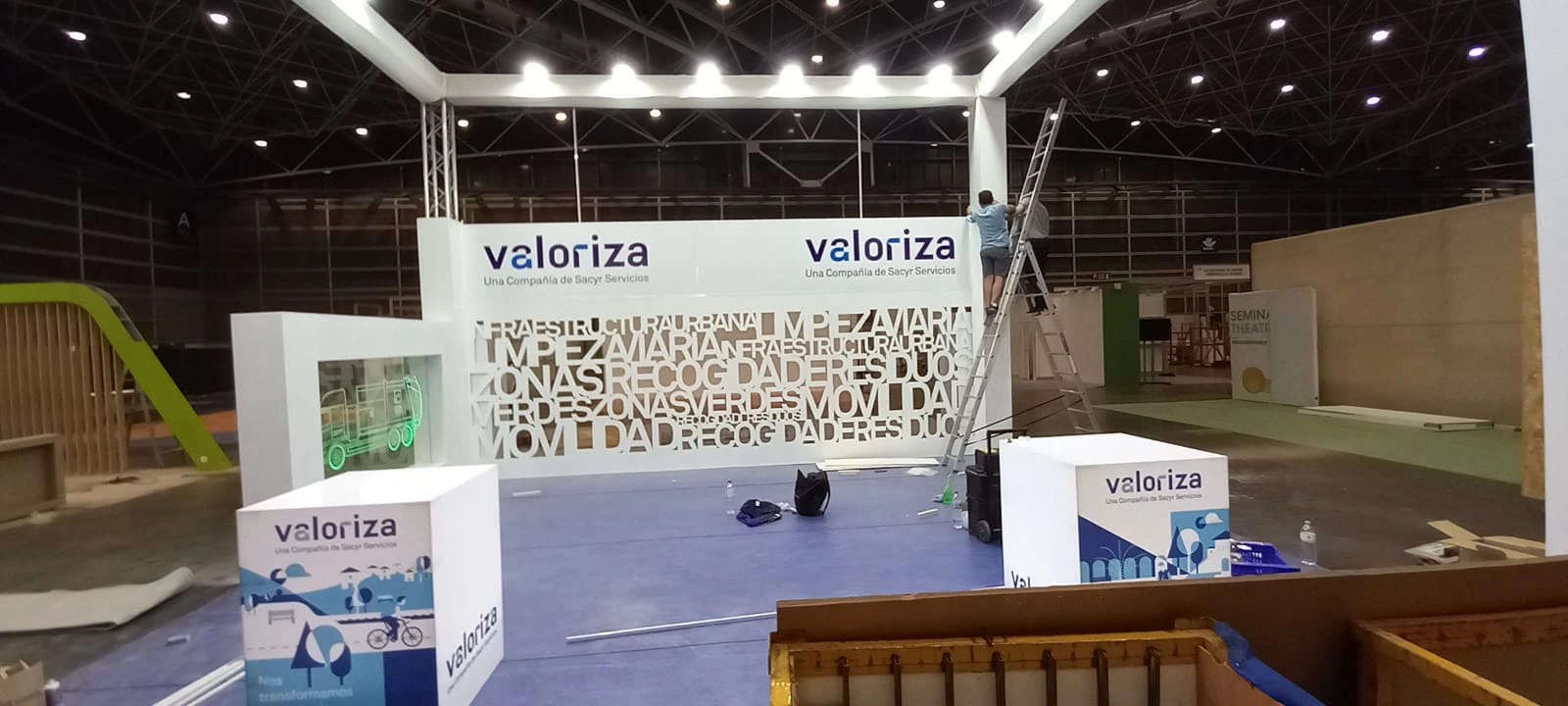 Vista general del stand de Valoriza durante la celebración de una exposición con un operario en una escalera