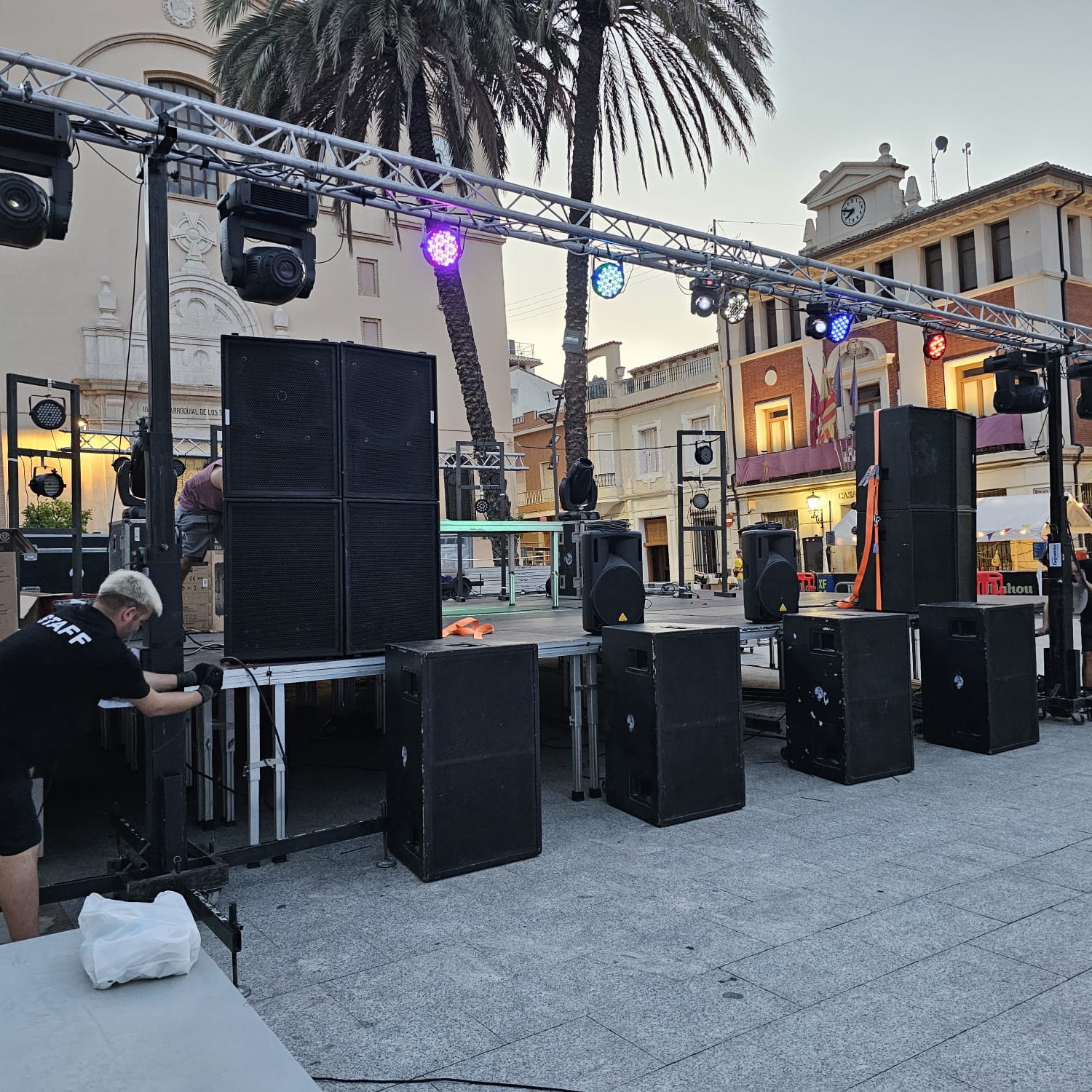 Preparativos de un evento en exterior con varios altavoces y focos de iluminación