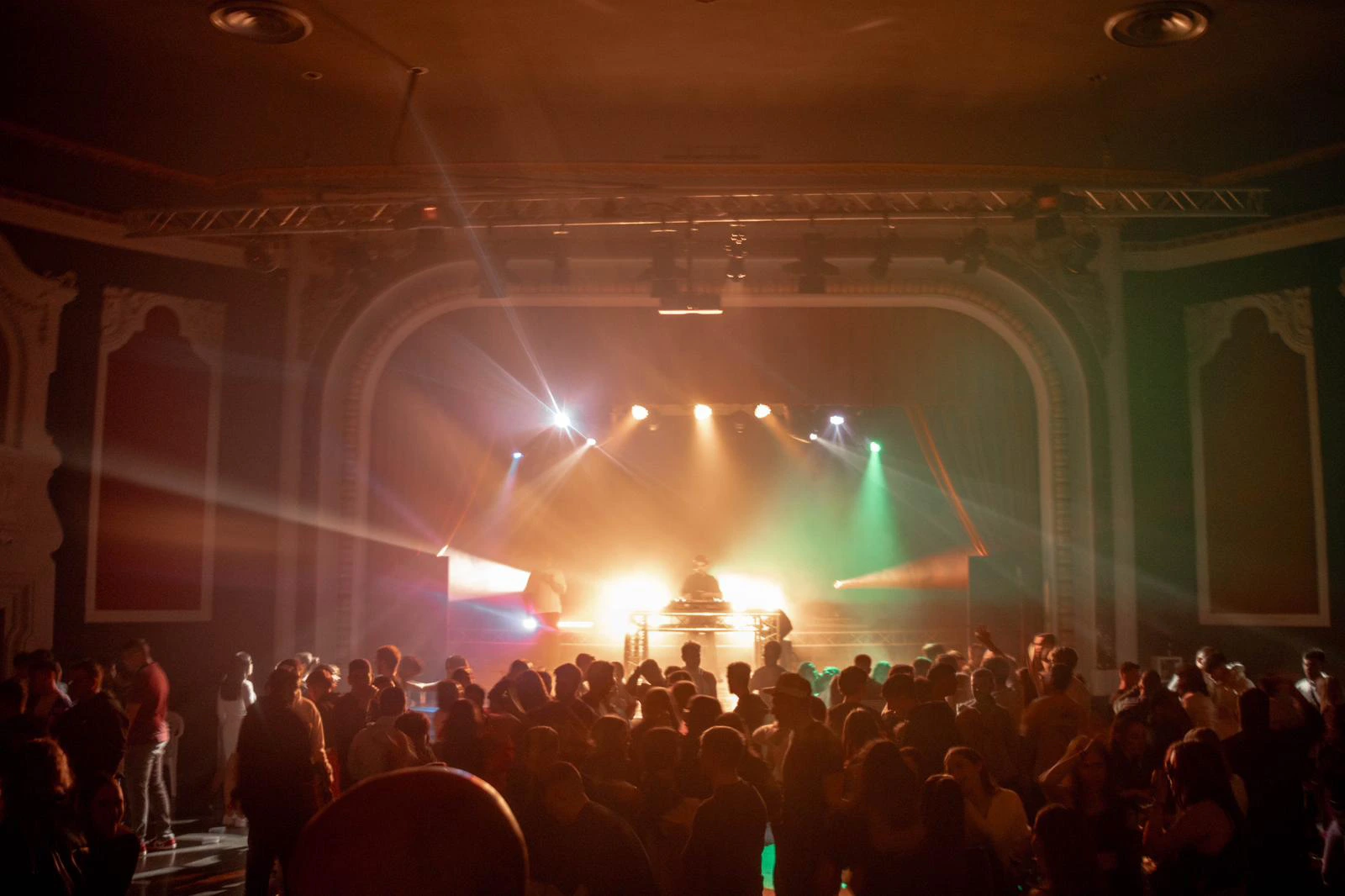 Vista de salón de un teatro con público bailando con instalación discomóvil y el escenario al fondo