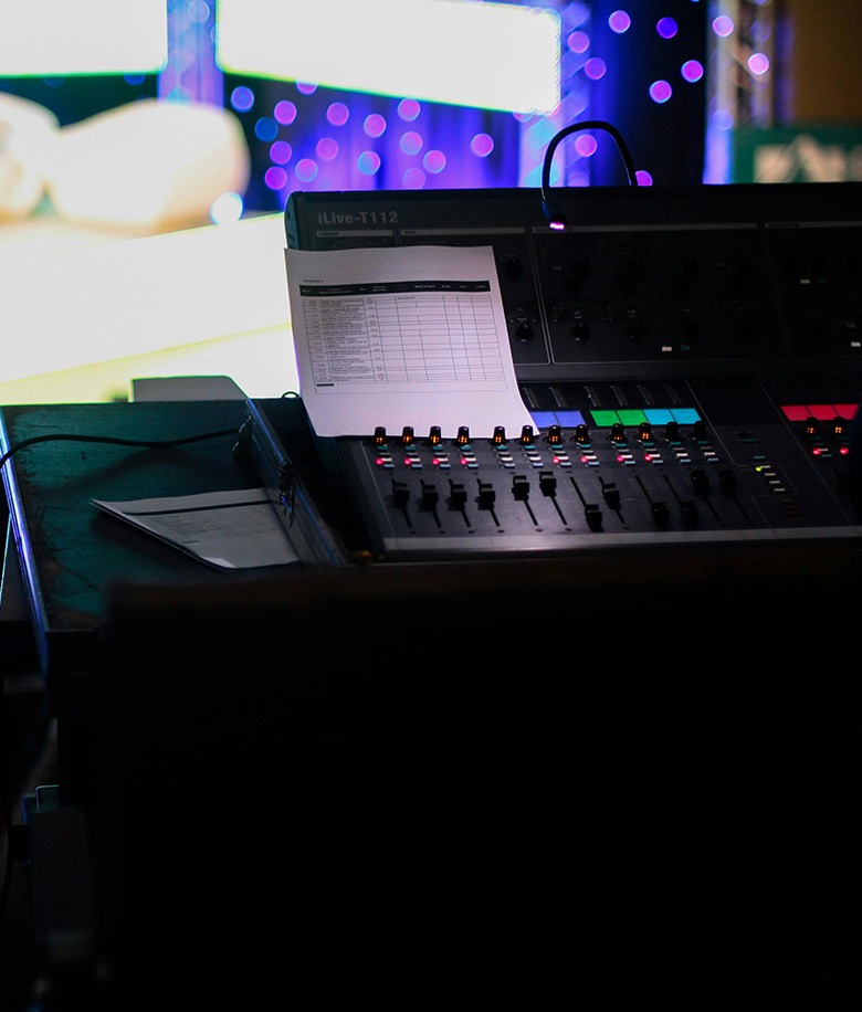 Vista de una mesa de sonido iluminada en un ambiente oscuro
